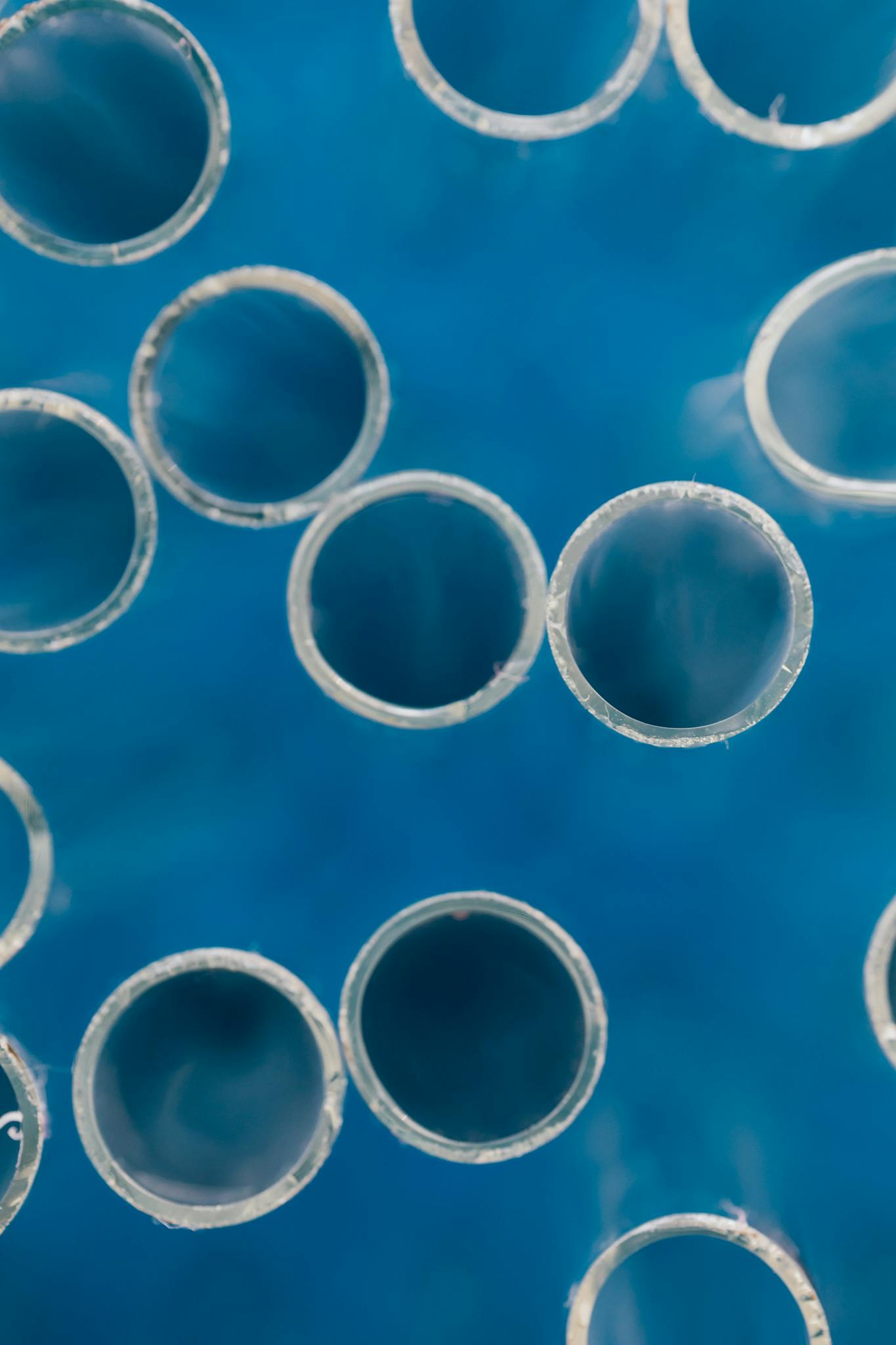 Close-up of transparent glass tubes against a vivid blue background. Ideal for science or technology themes.