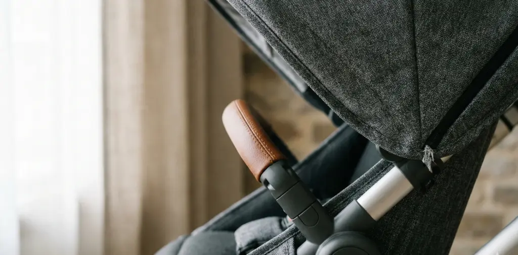 Detailaufnahme des Ledergiffs und der hochwertigen Stoffe eines Kinderwagens.