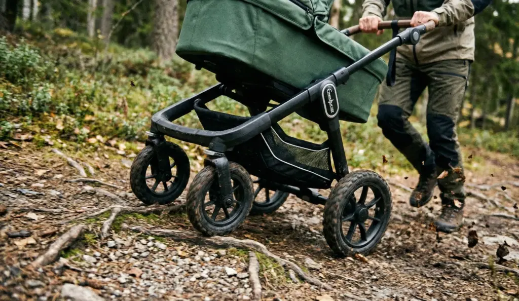 Emmaljunga NXT90 ähnlicher Kinderwagen im Gelände auf Waldweg mit Wurzeln