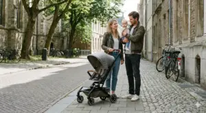 Eine Familie ist mit einem kompakten Kinderwagen entspannt in der Stadt unterwegs. Die Szene zeigt, wie alltagstauglich und leicht manövrierbar der Buggy im urbanen Umfeld ist.