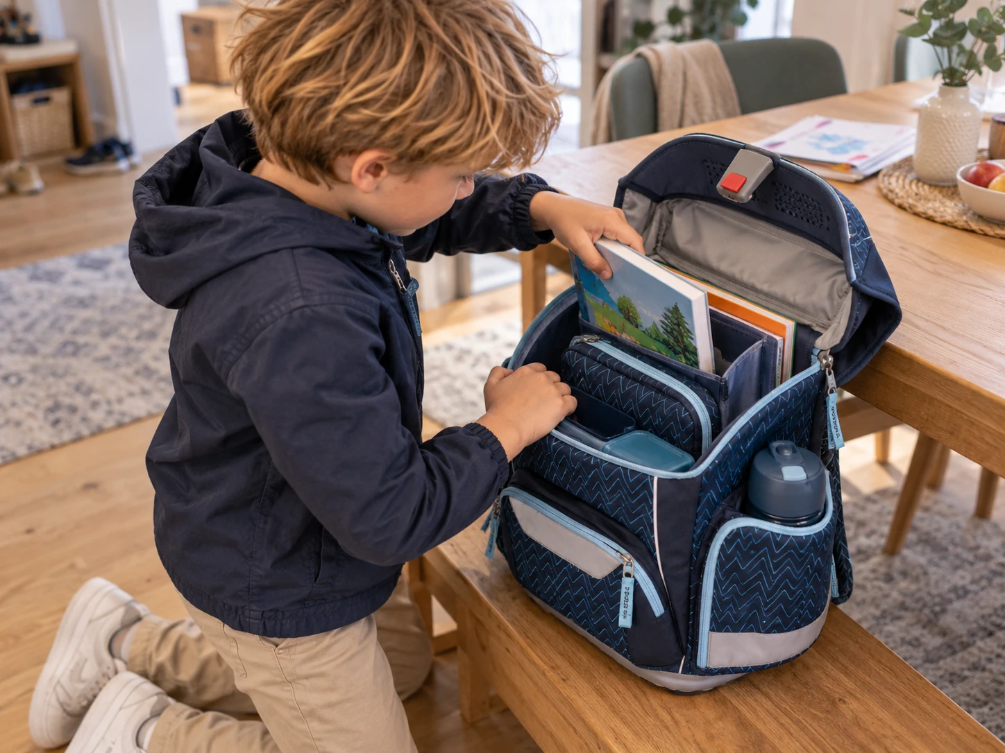 Junge packt Bücher in den geöffneten Step by Step BASIS Schulranzen